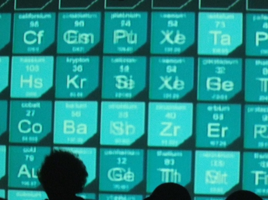 Close-up of the projected tiles, teal element symbols with heads in silhouette below