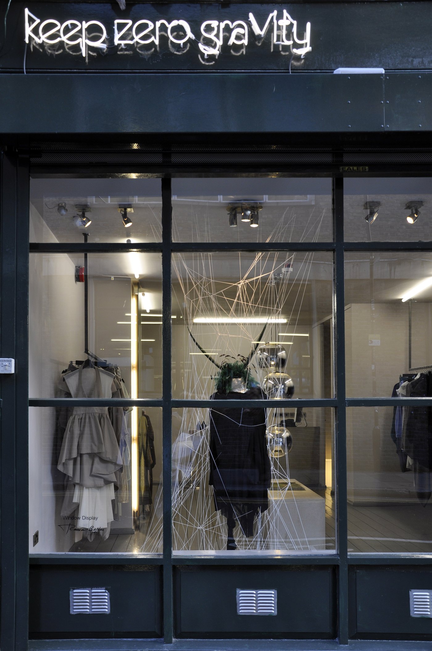 The shop window at night, a display with hanging strands and a mannequin
