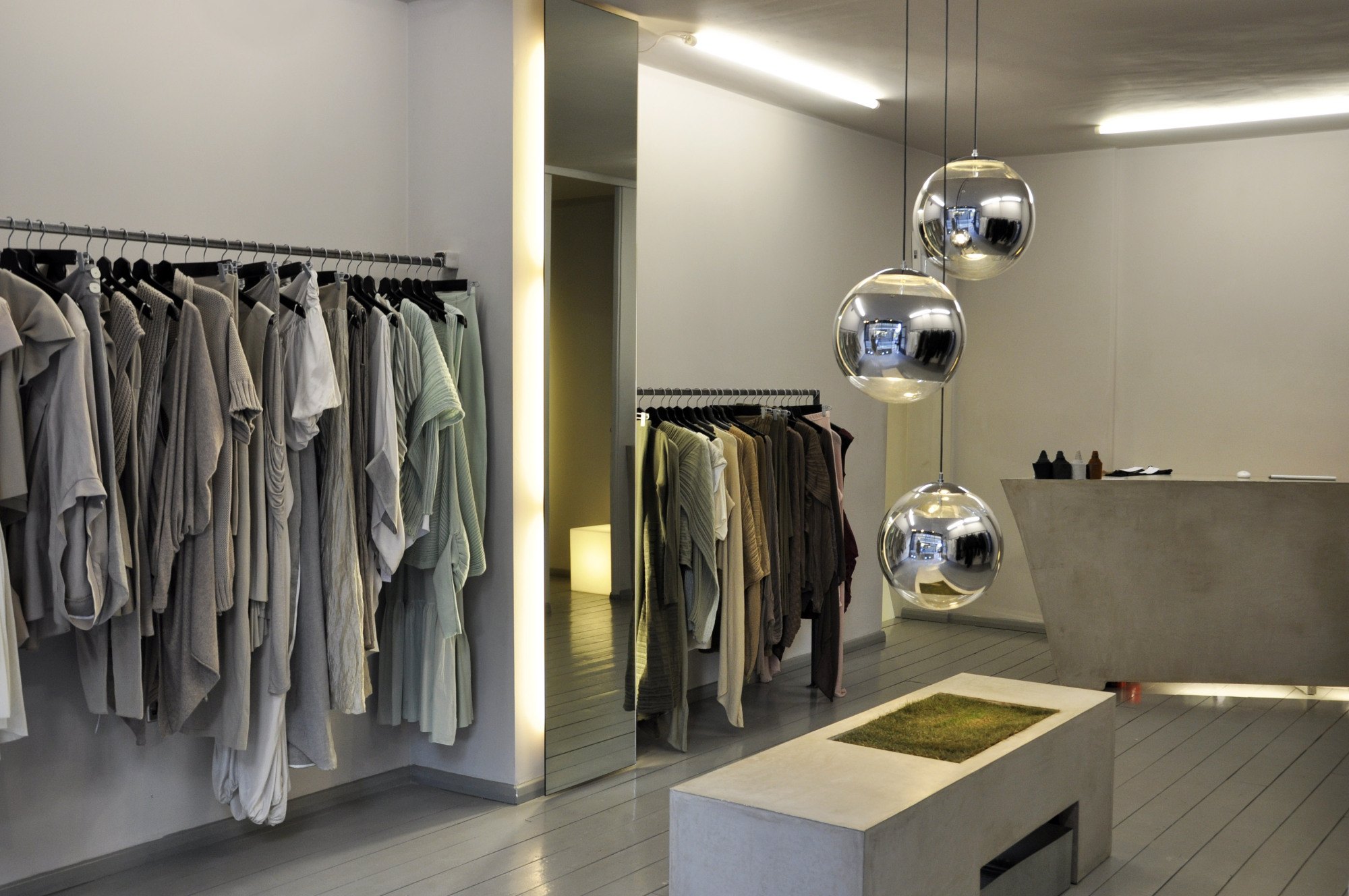 The shop floor: rails of pale clothes, a concrete counter and chrome spheres hanging overhead