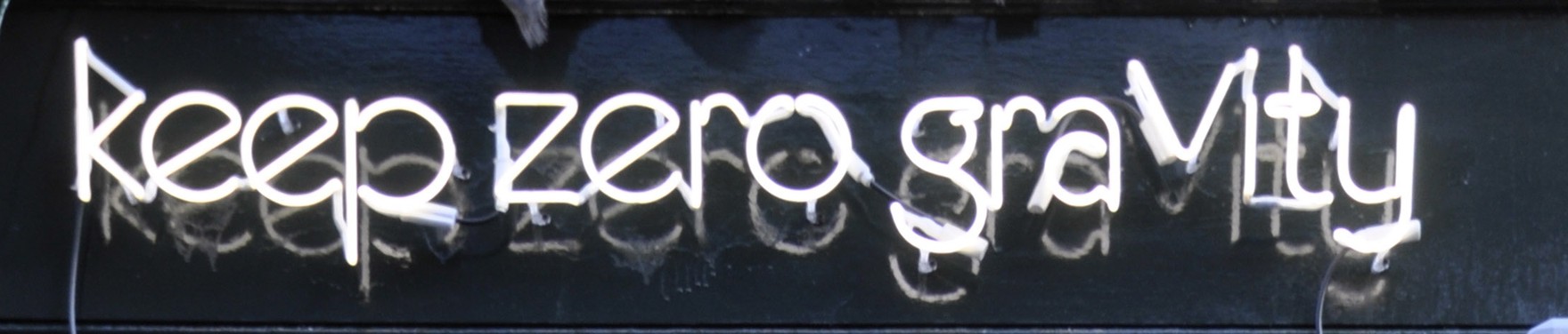 The neon sign reading 'keep zero gravity' above the door