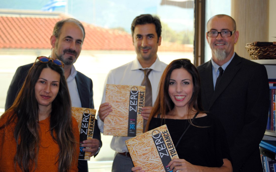 Five people holding copies of Issue 0, smiling, in an office
